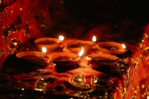 Traditional oil lamps glow warmly on vibrant red and gold fabrics, creating a festive ambiance.